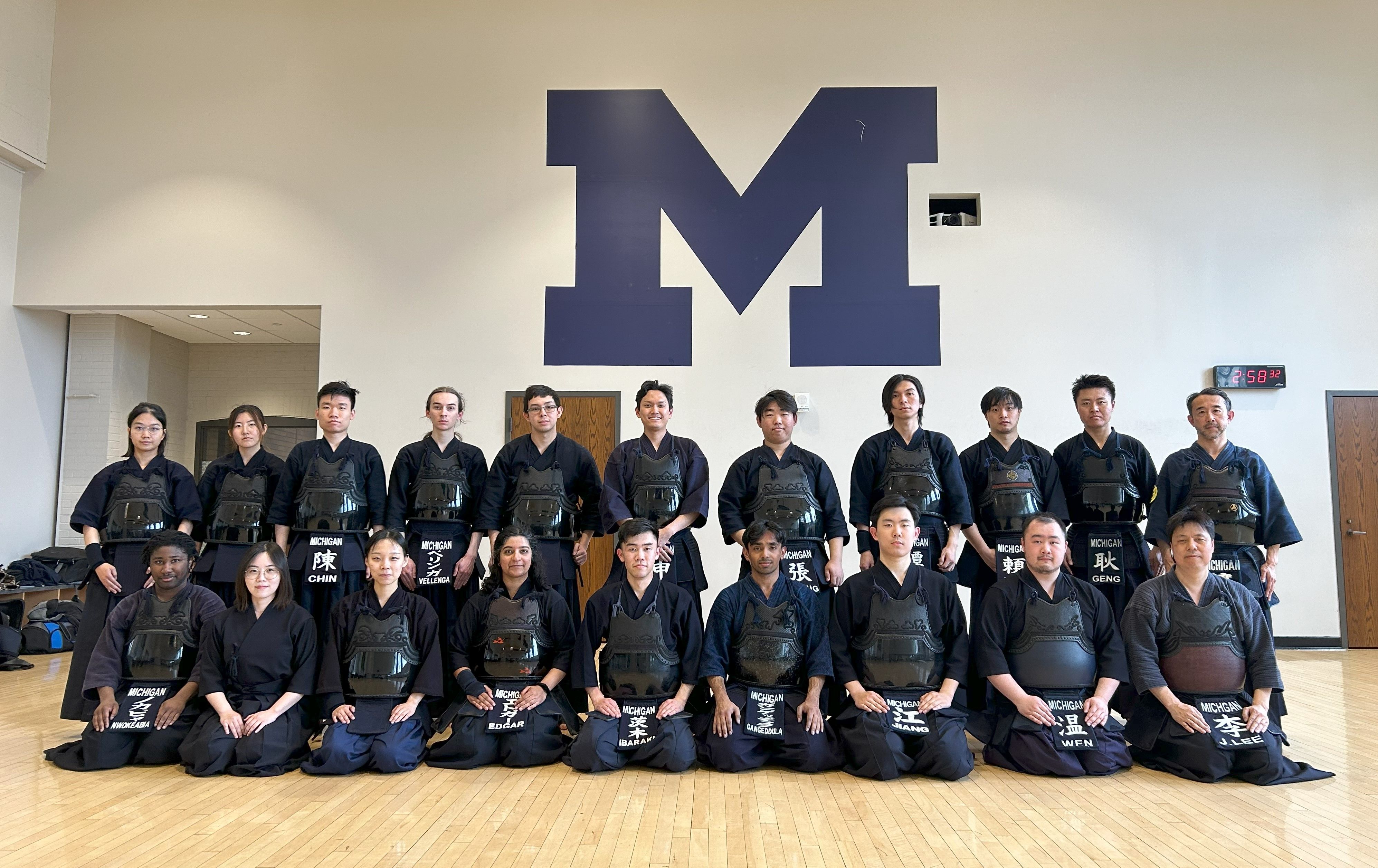 A group of 20 people in kendo armor with serious faces